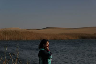 Full length of man standing on shore against clear sky