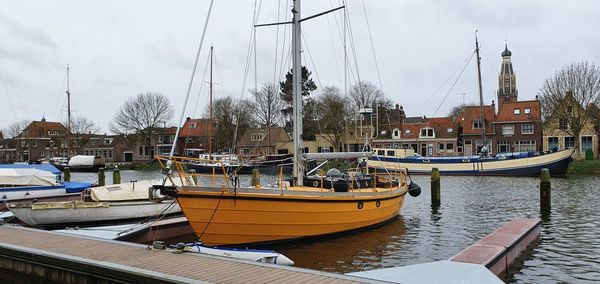 Boats moored at harbor against sky