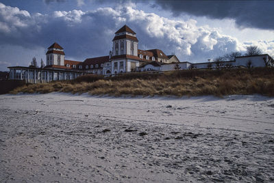 Buildings on beach against cloudy sky