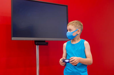 Boy playing video game against red background
