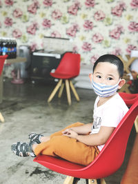 Asian boy wearing mask while sitting in shop during covid-19 situation 