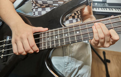 Teenager plays the bass guitar in home music studio