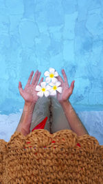 Low section of woman holding flowers in swimming pool