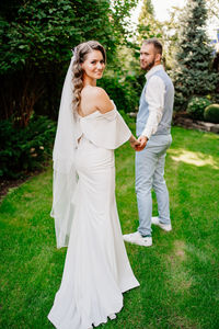 Happy couple standing on grass against plants