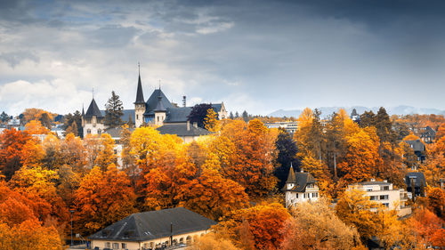 Trees and buildings against sky during autumn