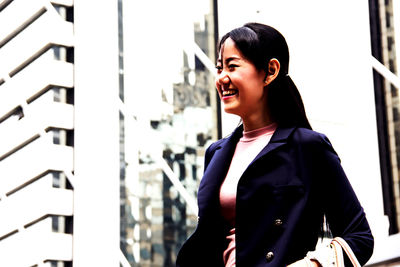 Side view of smiling young woman standing outdoors