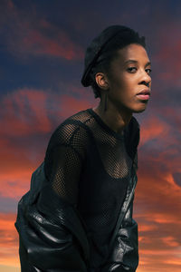 Young woman looking away against sky during sunset