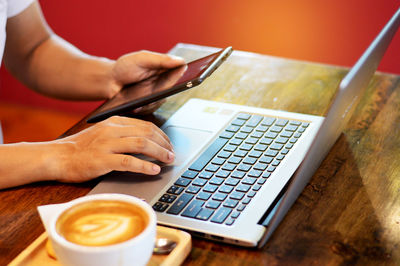 Cropped image of hand holding coffee cup on table