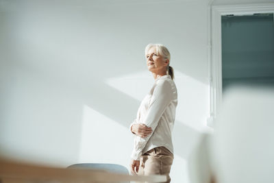 Senior businesswoman in front of wall at office