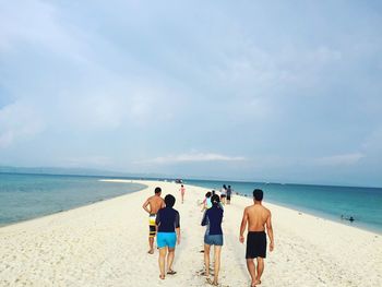 Rear view of people walking at beach