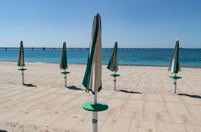 Deck chairs on beach against clear blue sky