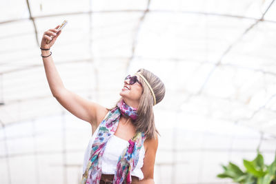 Smiling woman taking selfie with mobile phone