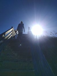 Low angle view of man standing on umbrella against sky