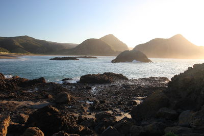 Scenic view of sea and mountains against clear sky