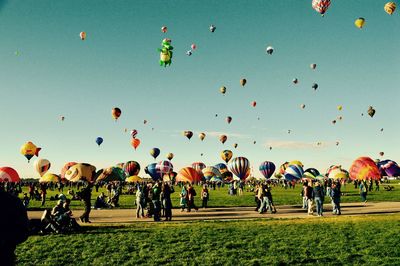 Crowd standing on field against hot air balloons