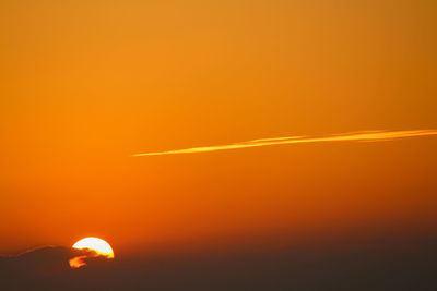 Low angle view of vapor trails in sky during sunset