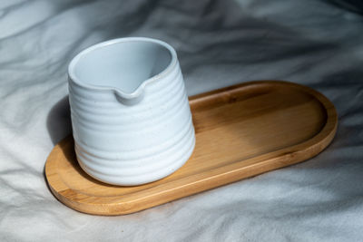 Mug made of white clay or ceramic mug on the wooden plate. subject on the cloth background