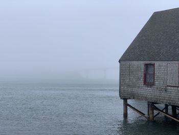 A fish smoking shack against the fog where you can barely see the bridge behind