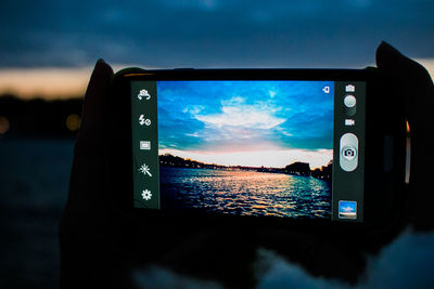 Close-up of camera on sea against sky during sunset