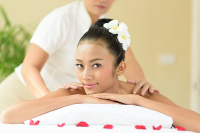 Midsection of masseuse giving massage to young woman relaxing at spa