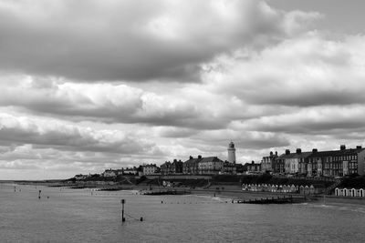 View of buildings by river against cloudy sky