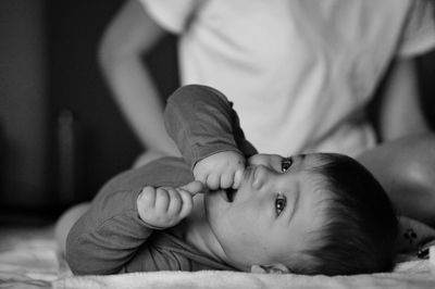Portrait of cute boy lying on bed at home cared by his mother