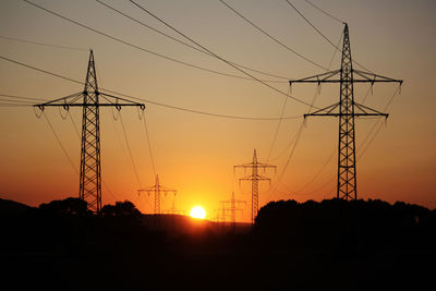 Sunset behind silhouette of electricity pylon