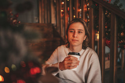 Portrait of candid authentic smiling handsome boy teenager using mobile phone at xmas home interior