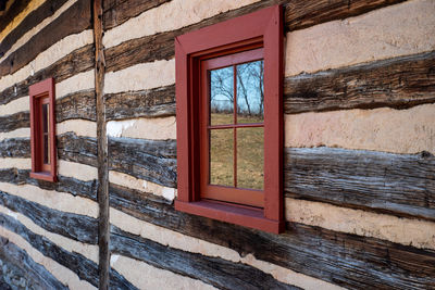 Exterior wall of colonial log cabin with landscape reflected in window