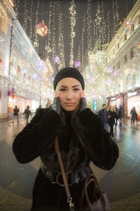 Portrait of young woman standing on street at night