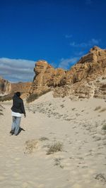 Rear view of man walking on desert against sky