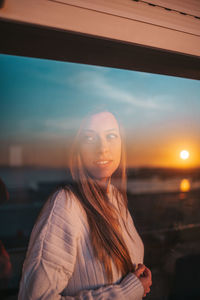 Portrait of young woman standing against sky during sunset