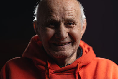 Close-up of senior man against black background