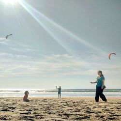 Children playing on beach against sky