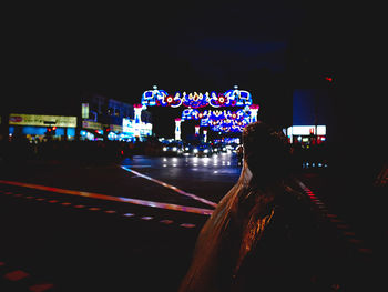 Rear view of woman on illuminated street at night
