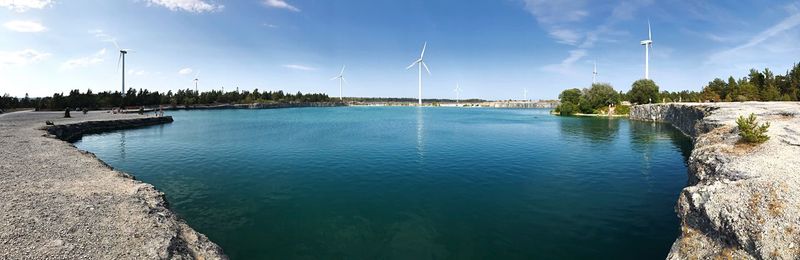 Panoramic view of lake and windmills against sky