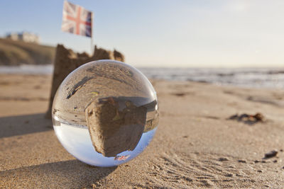 Close-up of sunglasses on beach against sky