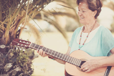 Happy senior woman playing guitar