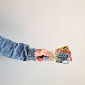 Close-up of hand holding paper over white background