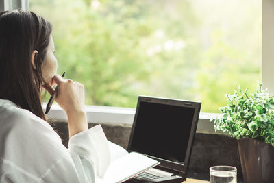 Woman using phone while sitting on table