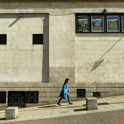 Full length side view of woman walking against building