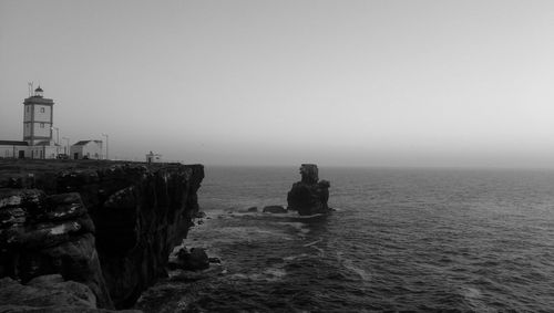 Lighthouse of cape carvoeiro on cliff by sea against clear sky