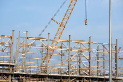 Low angle view of cranes against sky