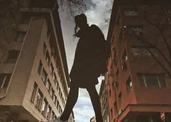 Low angle view of man standing by buildings in city