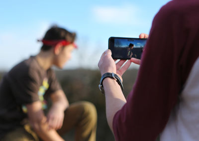 Midsection of person photographing friend
