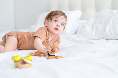 Cute baby with toy on bed at home
