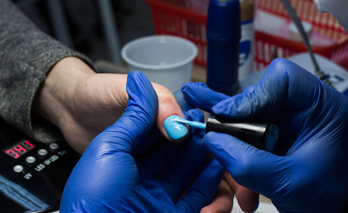 Close-up of beautician applying nail polish on finger of woman