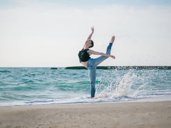 Full length of woman ballet dancing at beach