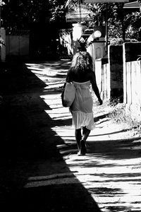 Rear view of woman walking on footpath