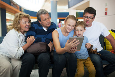Happy family looking at digital tablet while sitting at airport terminal